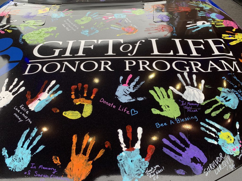 To raise awareness for organ donation, many lend a hand for special paint job on race car. Handprints for Hope event.