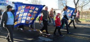 Family members of organ and tissue donors carry Memorial Quilts to start the Donor Dash 3k Walk.
