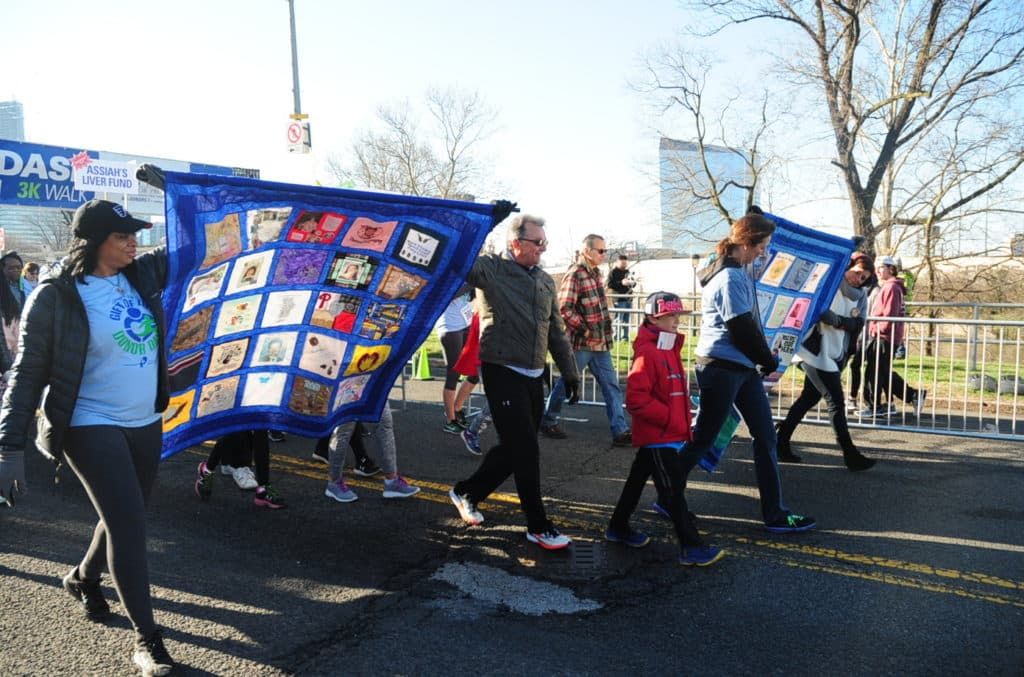 Family members of organ and tissue donors carry Memorial Quilts to start the Donor Dash 3k Walk.