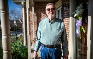 A man stands outside a house.