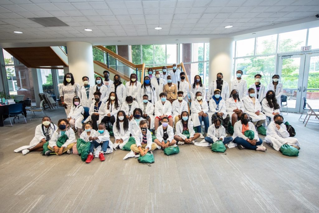 Kids and adults sit and stand as they pose for a picture