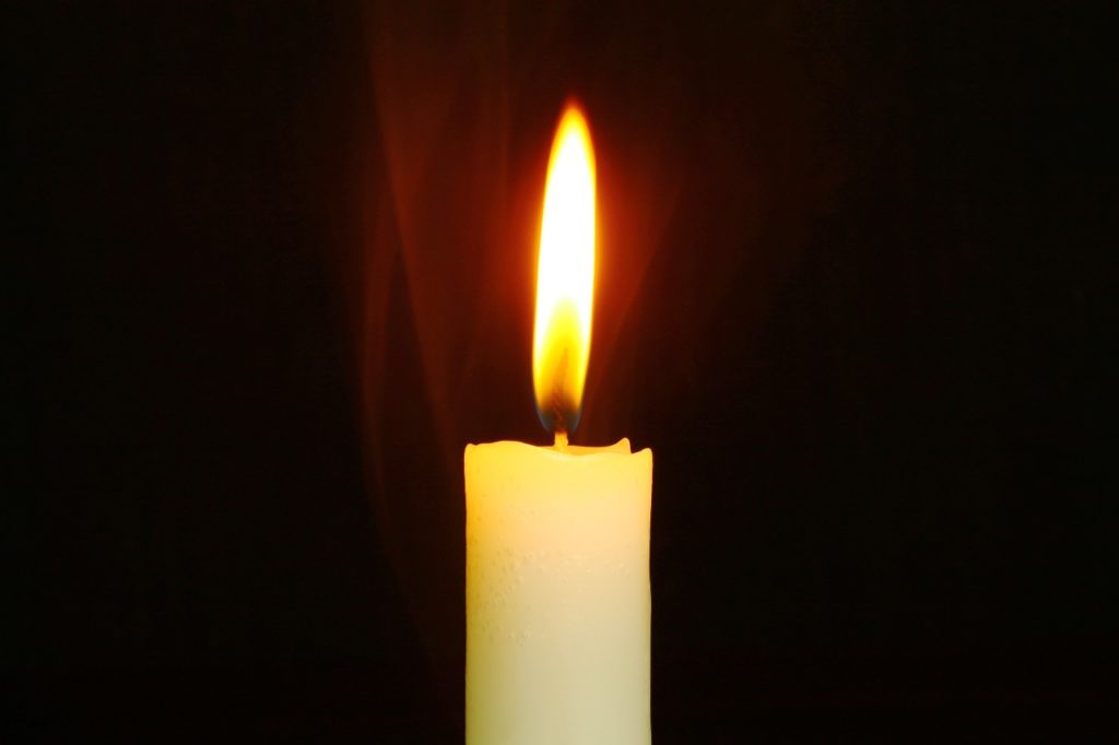 A candle burns in the dark
