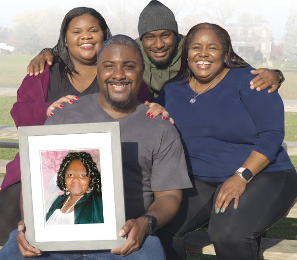 Family members sit together and hold a framed photo of their mother.