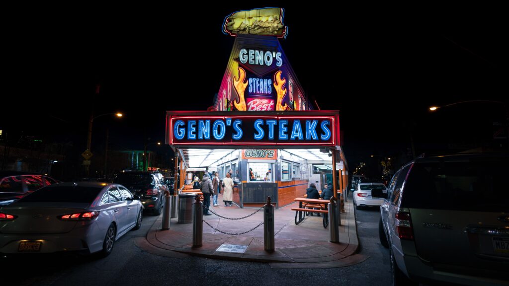 A photo of the restaurant Geno's Steaks in Philadelphia lit up at night. 