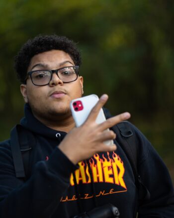 A young man poses for a photo with an iPhone in his hands.