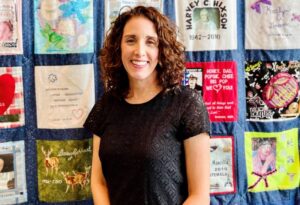 Gift of Life Donor Program's Lara Moretti stands in front of a quilt