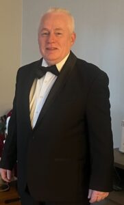 A man in a tuxedo poses for a photo.