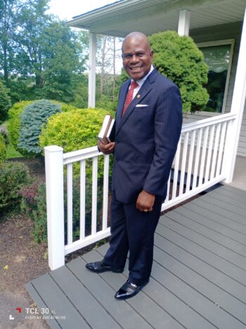 A man dressed in a suit and holding a book poses for a picture.