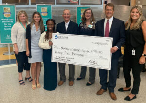 A group of people hold a big, decorative check signifying Gift of Life's grant to Nemours.