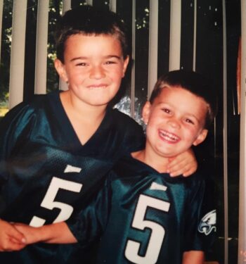 Two young men pose for a picture in their Eagles jersey.