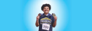 A young man smiles while holding two medals he won at the 2024 Transplant Games of America.